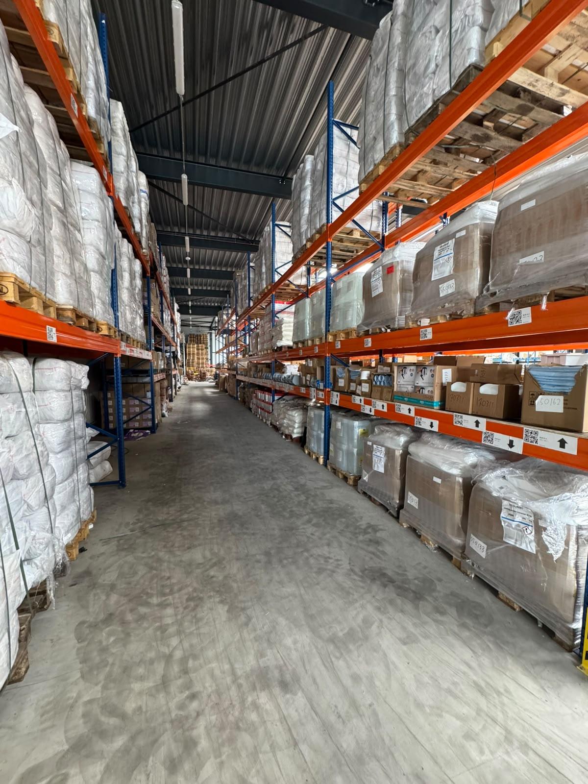 Racking with white bales of cotton rags and pallets of boxed goods